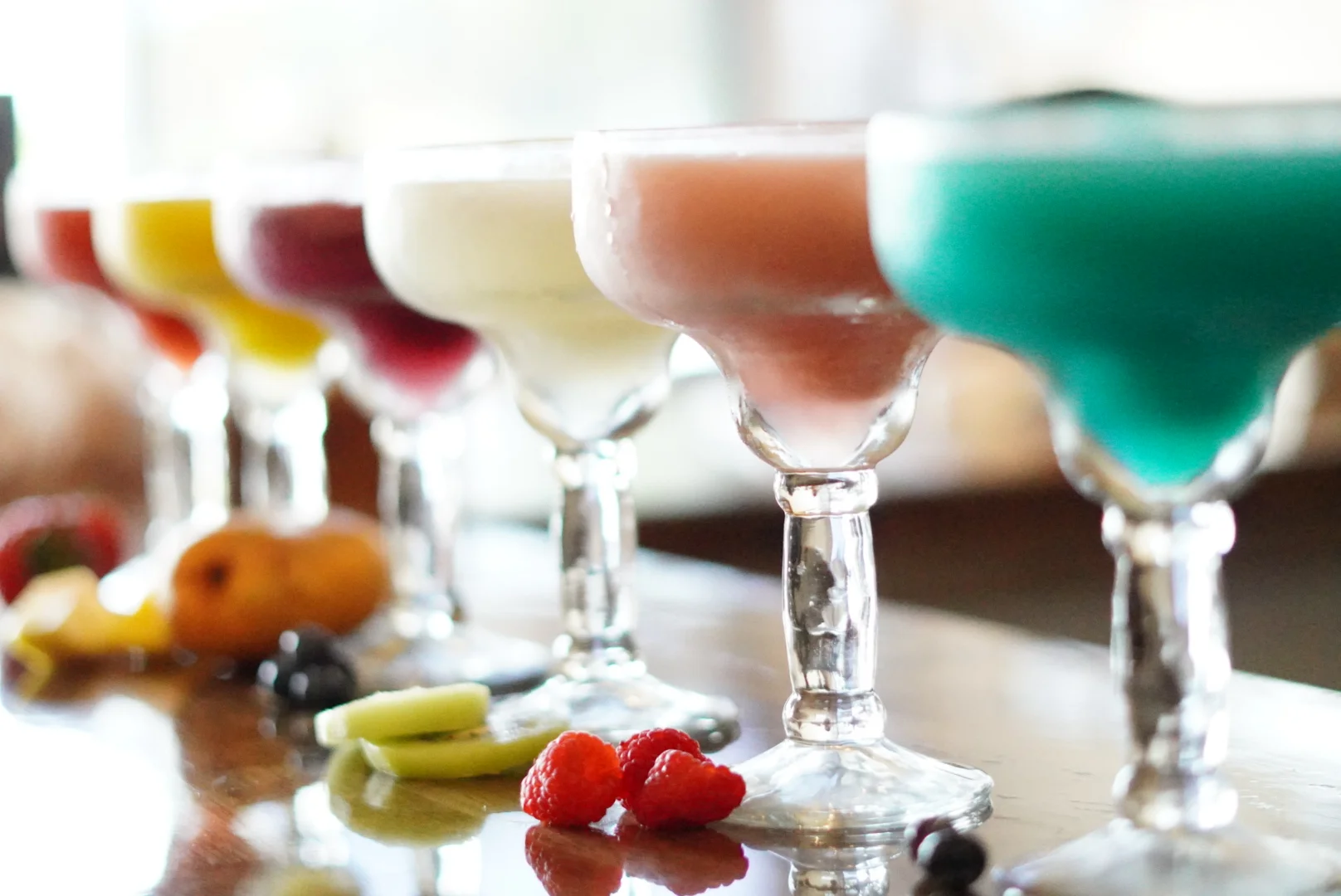 Colorful margaritas in elegant glasses at a bar