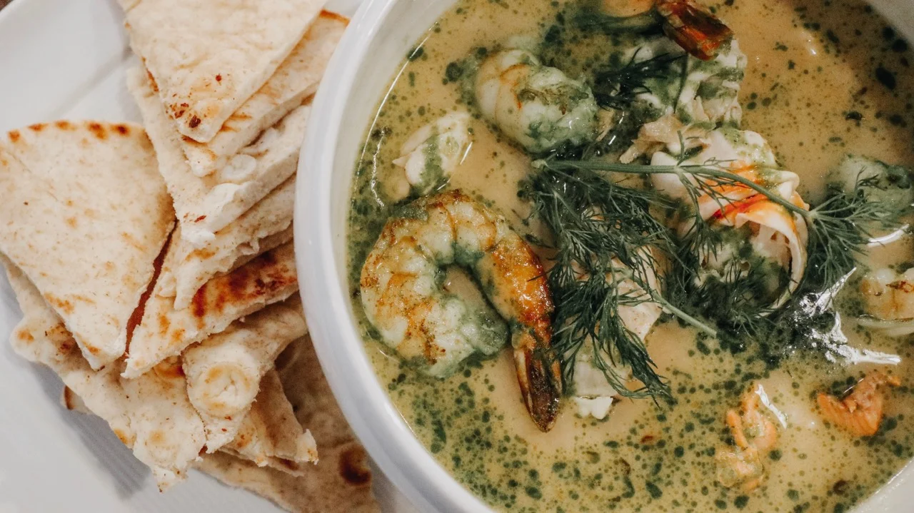 Bowl of Thai green curry with shrimp and flatbread