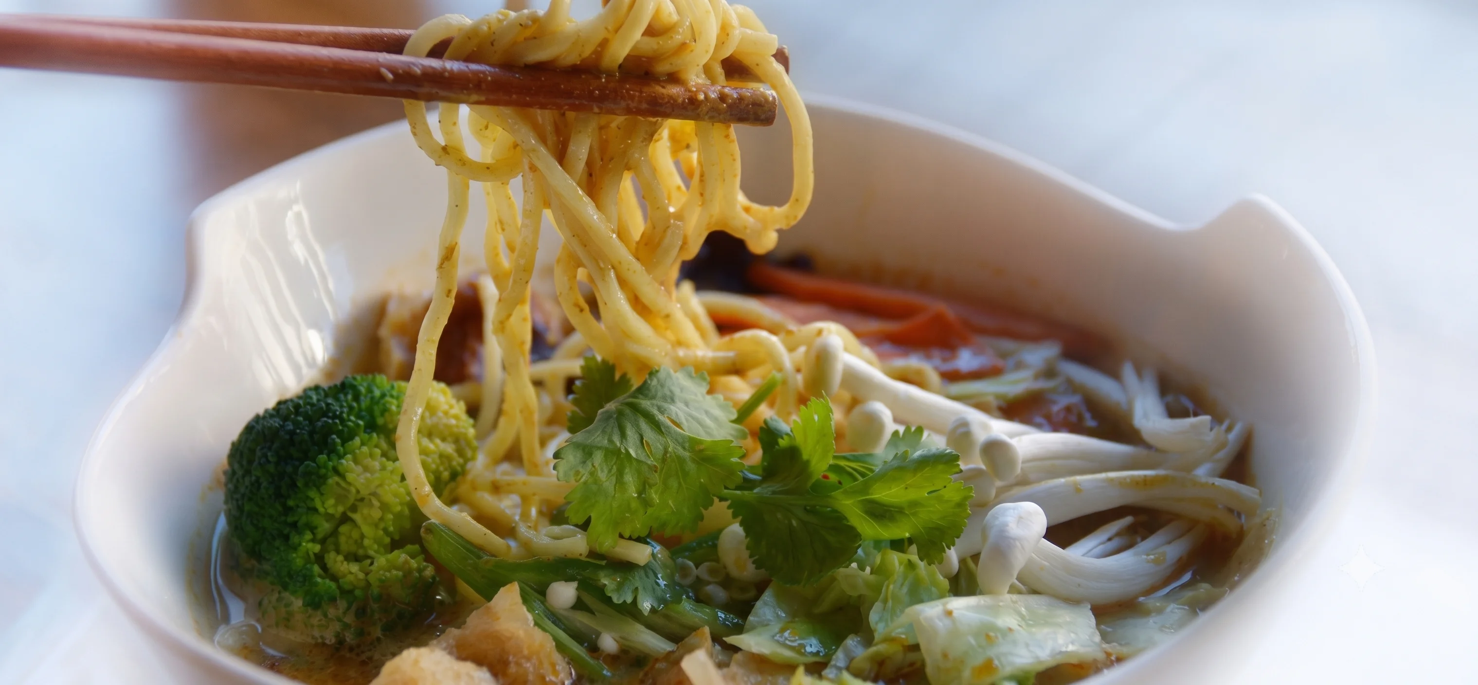 Bowl of Thai curry noodles with fresh herbs