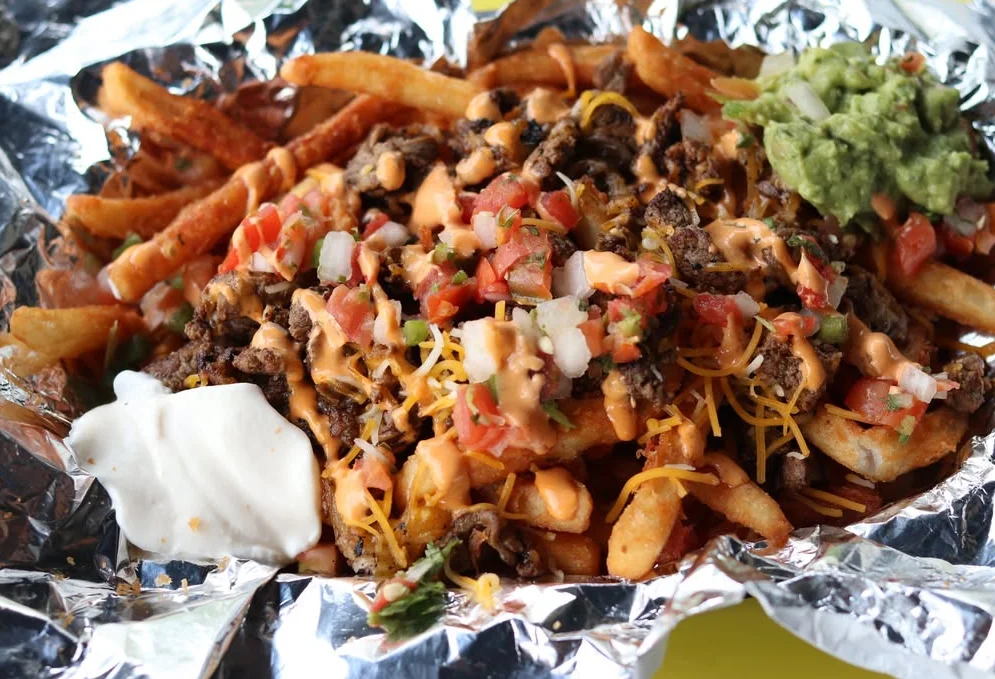 Loaded carne asada fries topped with queso sauce, pico de gallo, sour cream and fresh guacamole at Stuffed Burritos