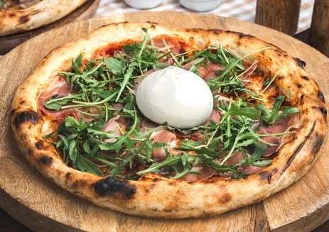 Italian pizza with prosciutto and arugula topped with burrata
