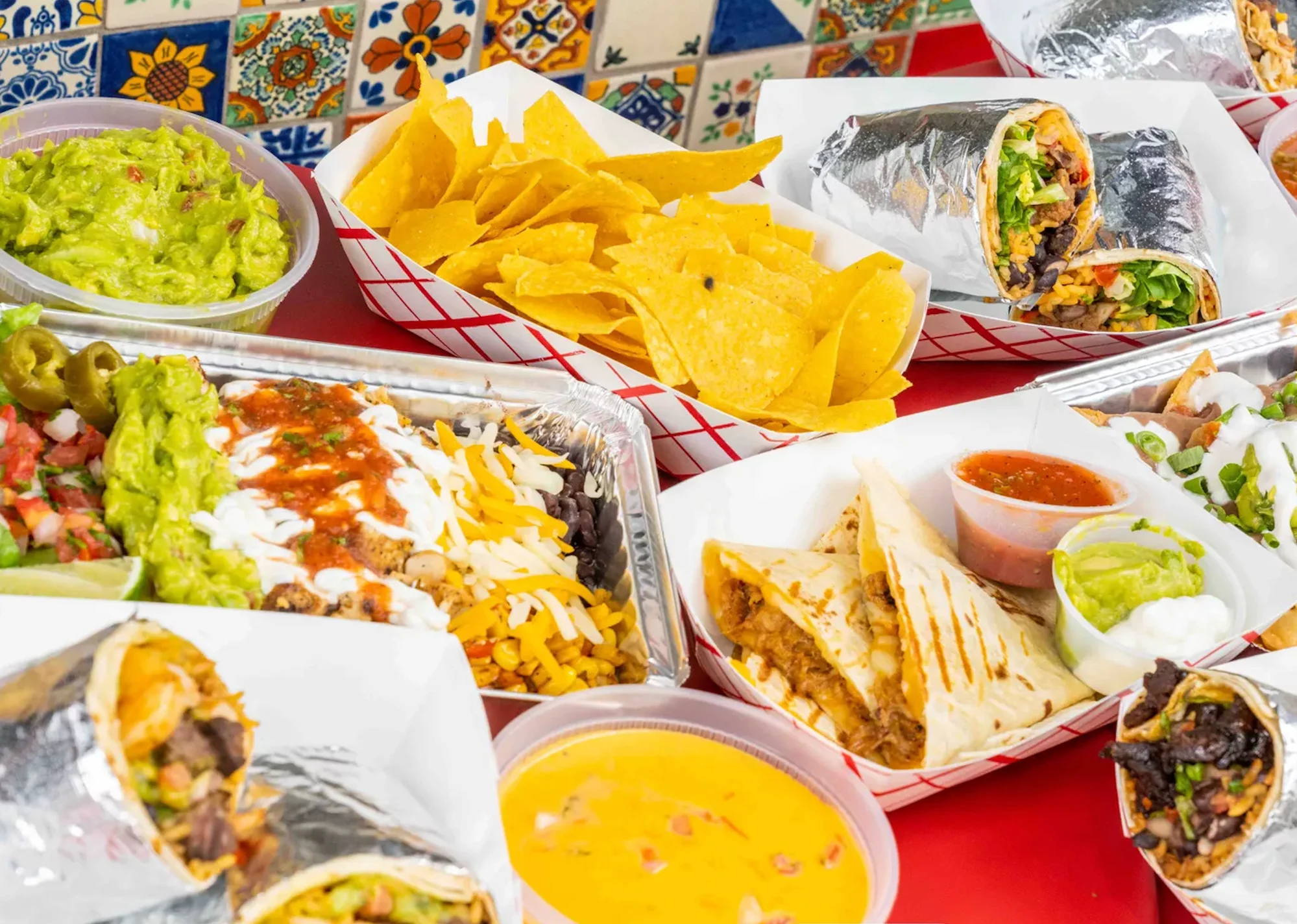 Colorful Mexican feast with burritos, guacamole, and tortilla chips