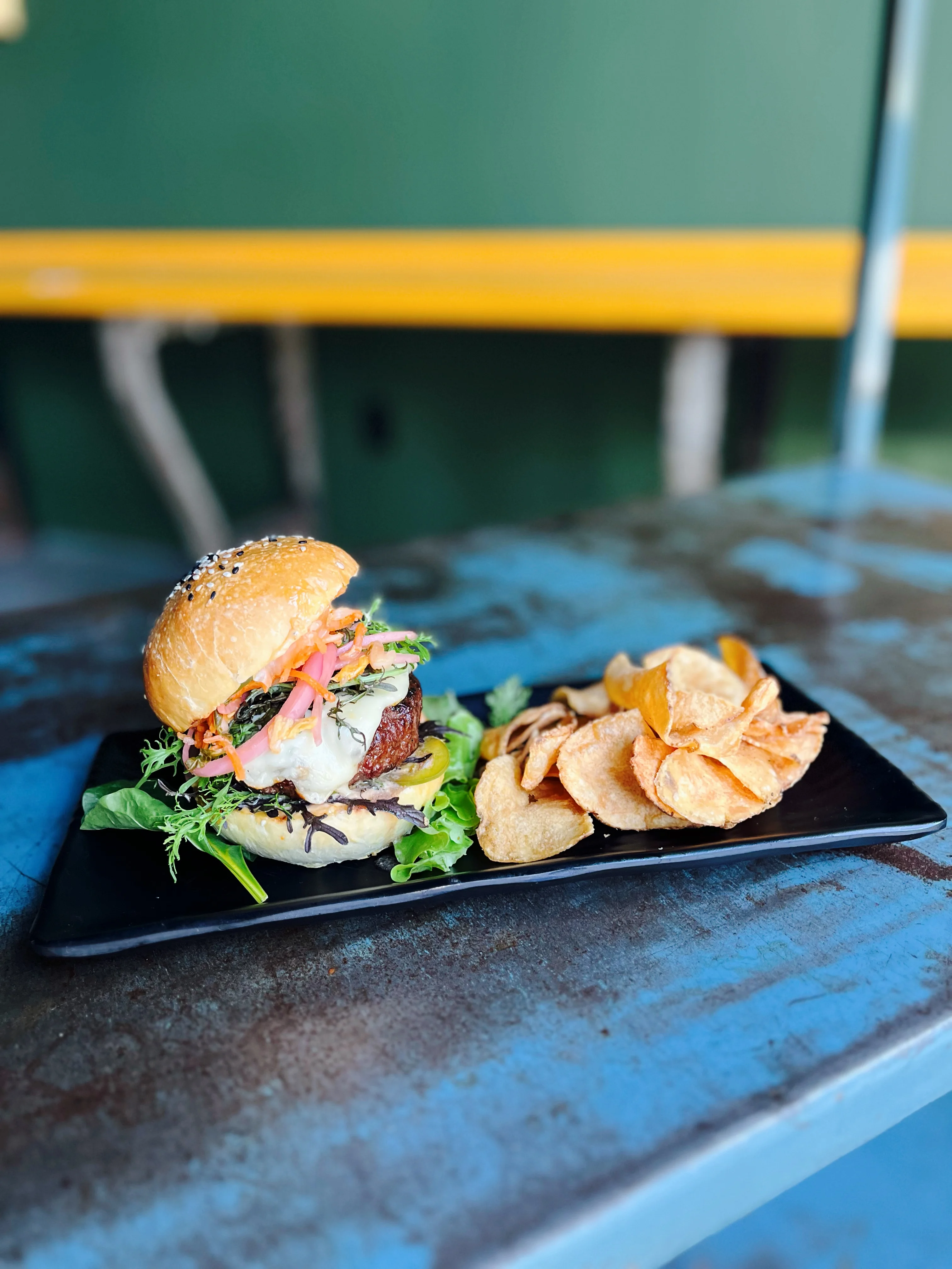 Gourmet burger with house-made chips on a black plate