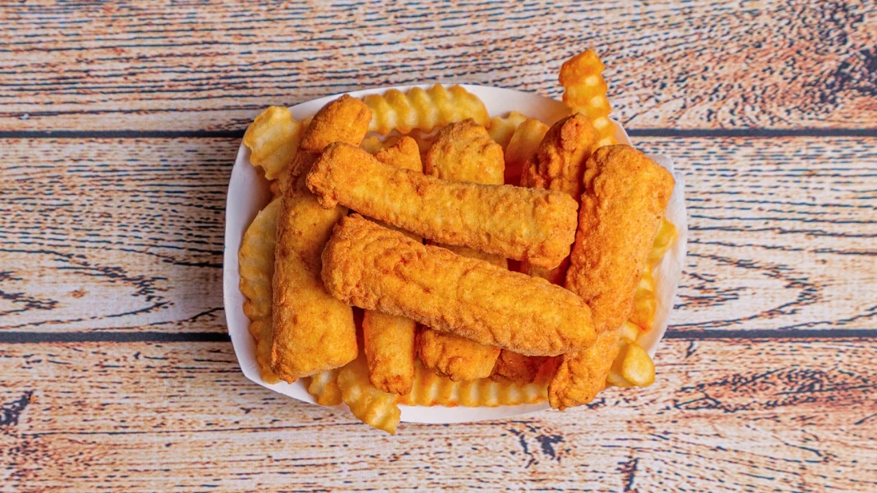 A plate filled with crispy fried chicken tenders and crinkle-cut fries, arranged appetizingly.