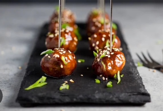 Asian-style meatballs with sesame and green onions on a slate platter