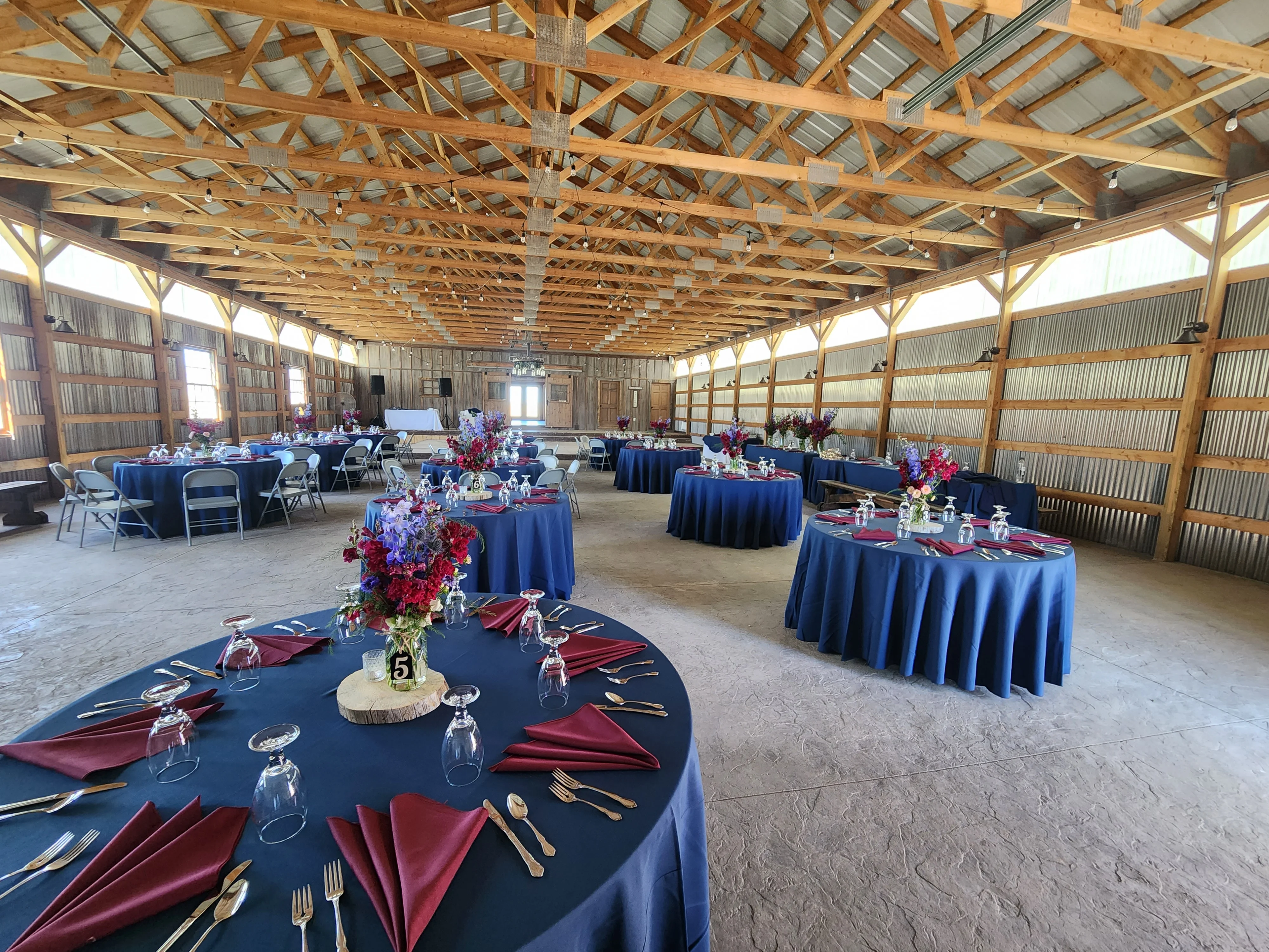 Tables set with china & linens for a barn wedding reception