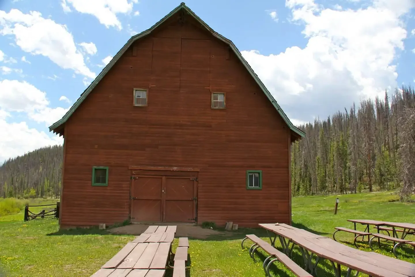 Rustic red barn with picnic tables in a scenic outdoor setting