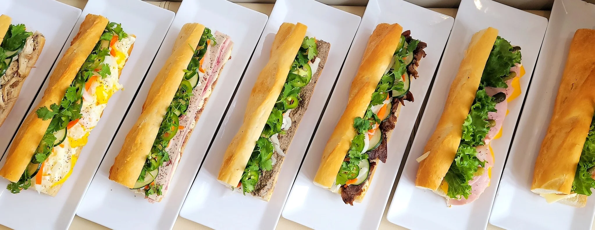 Assorted Vietnamese banh mi sandwiches on white plates