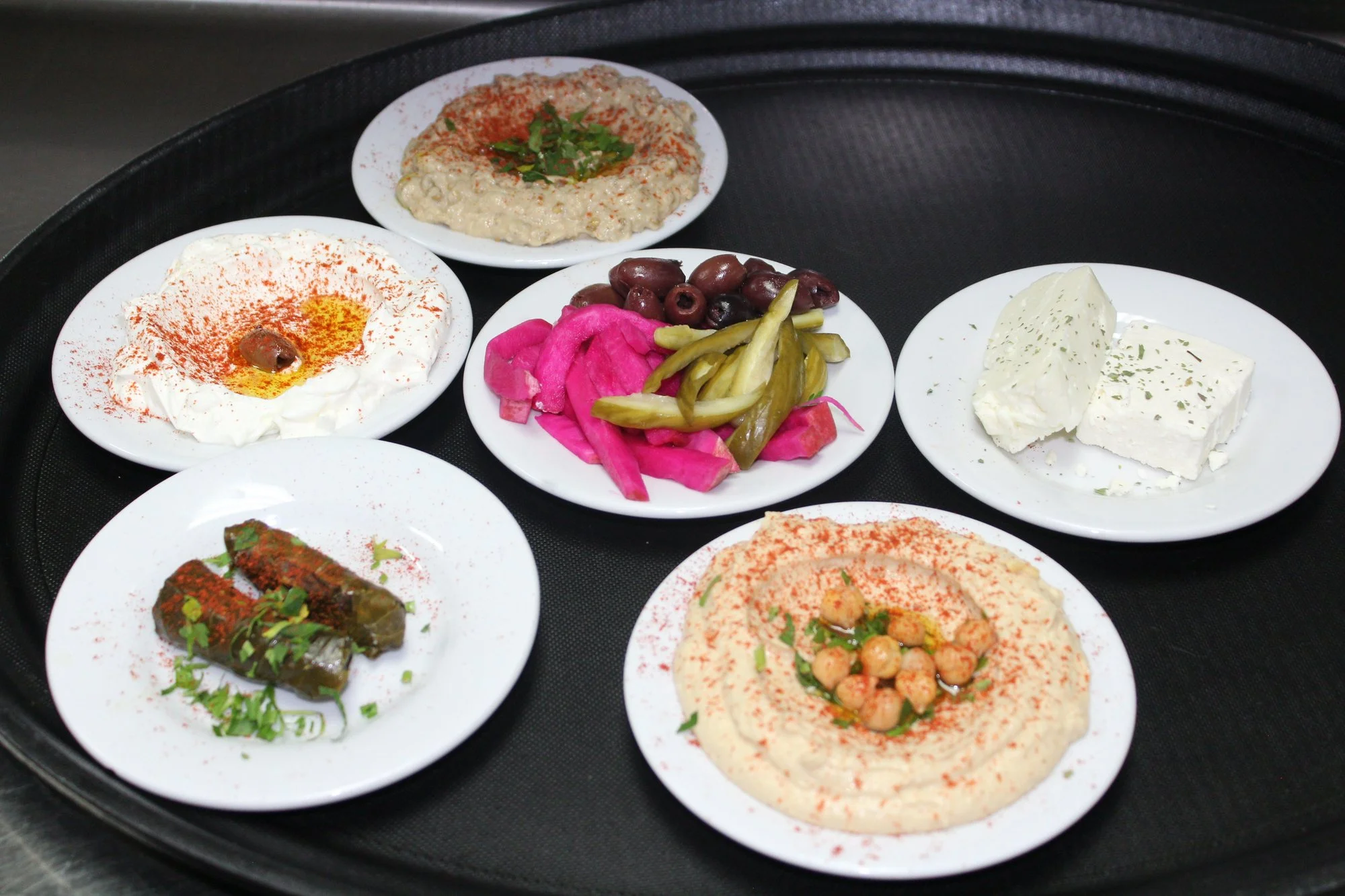 Mezza spread of hummus, labni, grape leaves and pickles on a tray at Khoury's