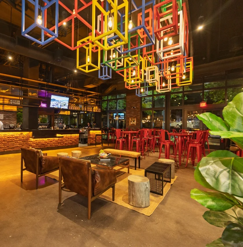 Modern restaurant interior with colorful lighting and seating.
