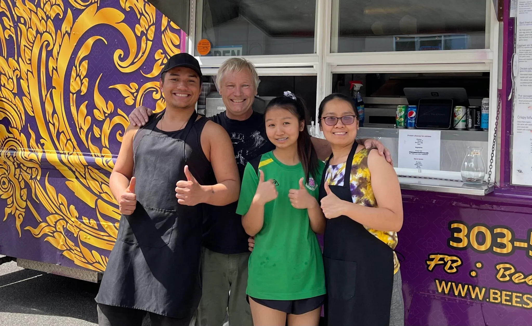 Food truck team giving thumbs up outside their vibrant food truck