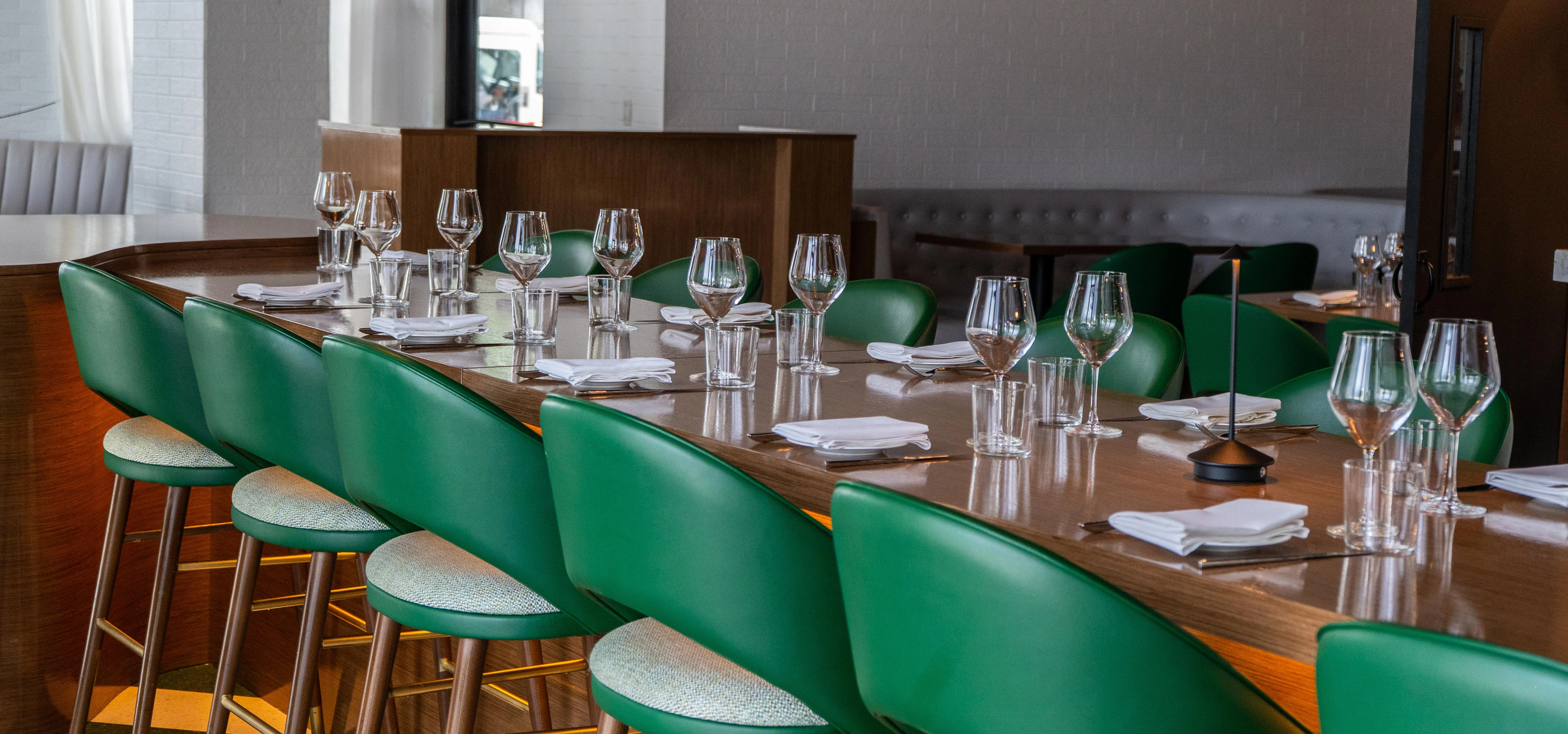 Modern restaurant interior with green bar stools and elegant table settings