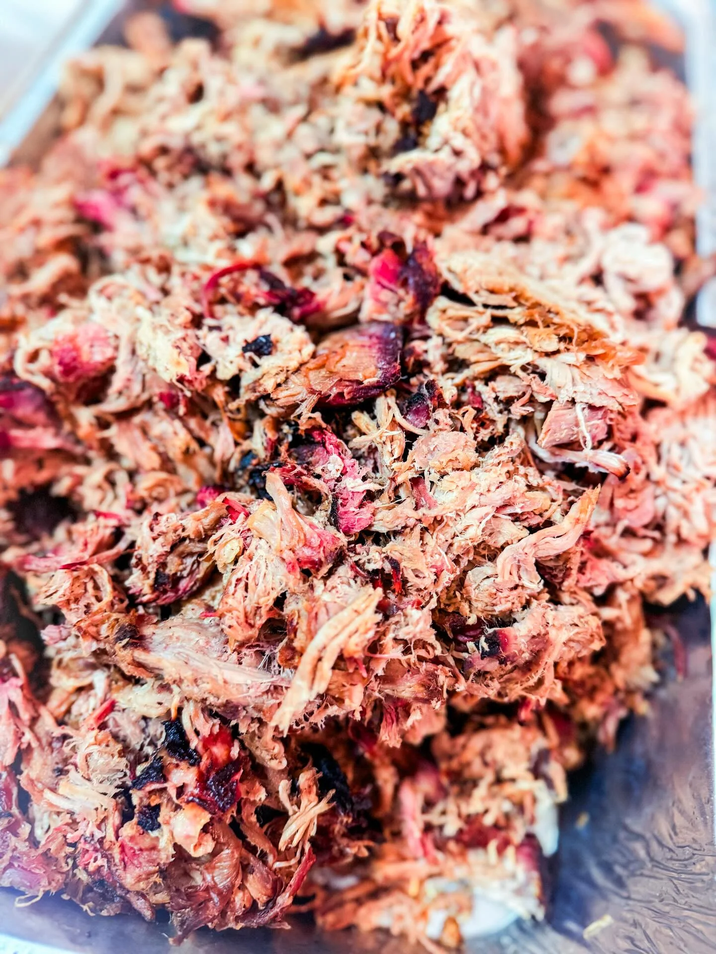 A close-up of a piece of smoked meat wrapped in foil, showing a caramelized crust.