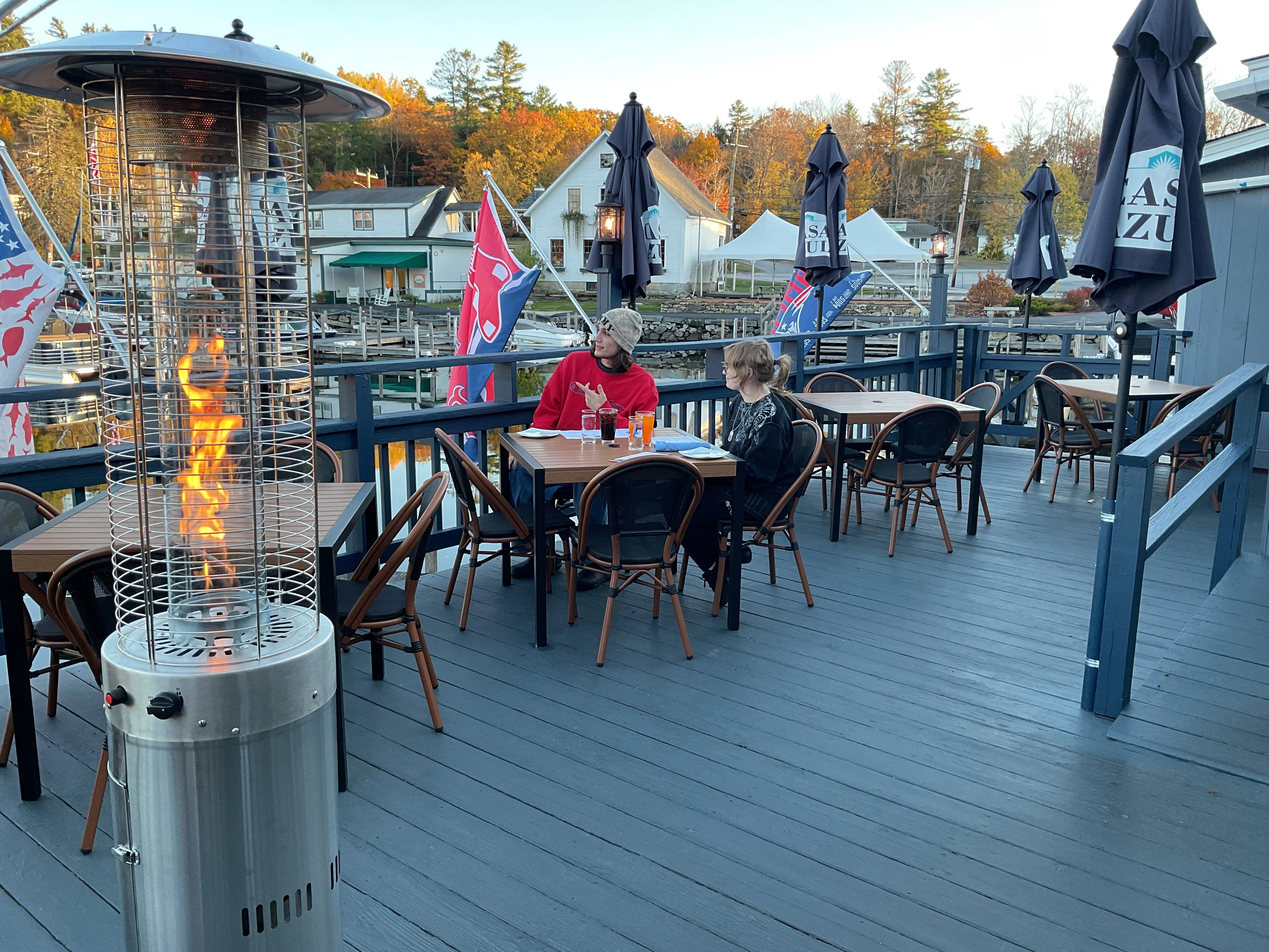 Outdoor dining area with patio heaters and autumn scenery