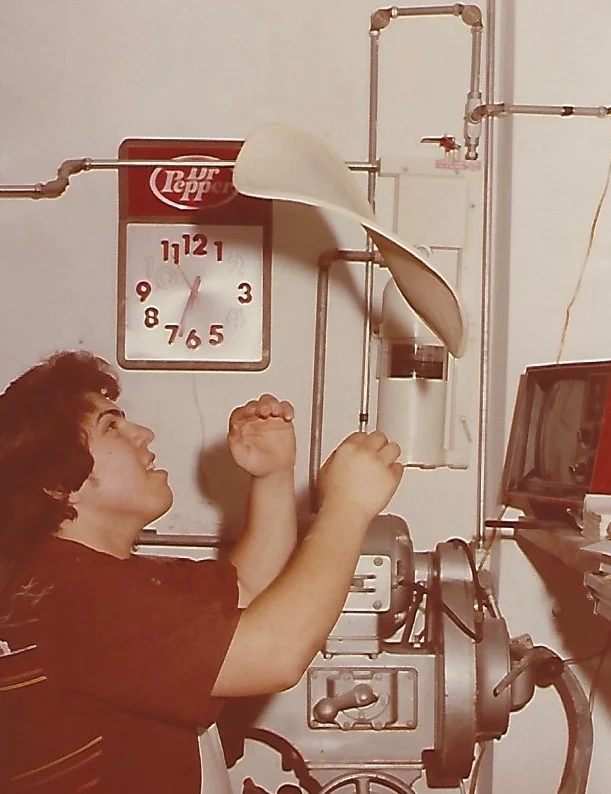 A woman in a red outfit preparing dough in a kitchen with baking equipment.