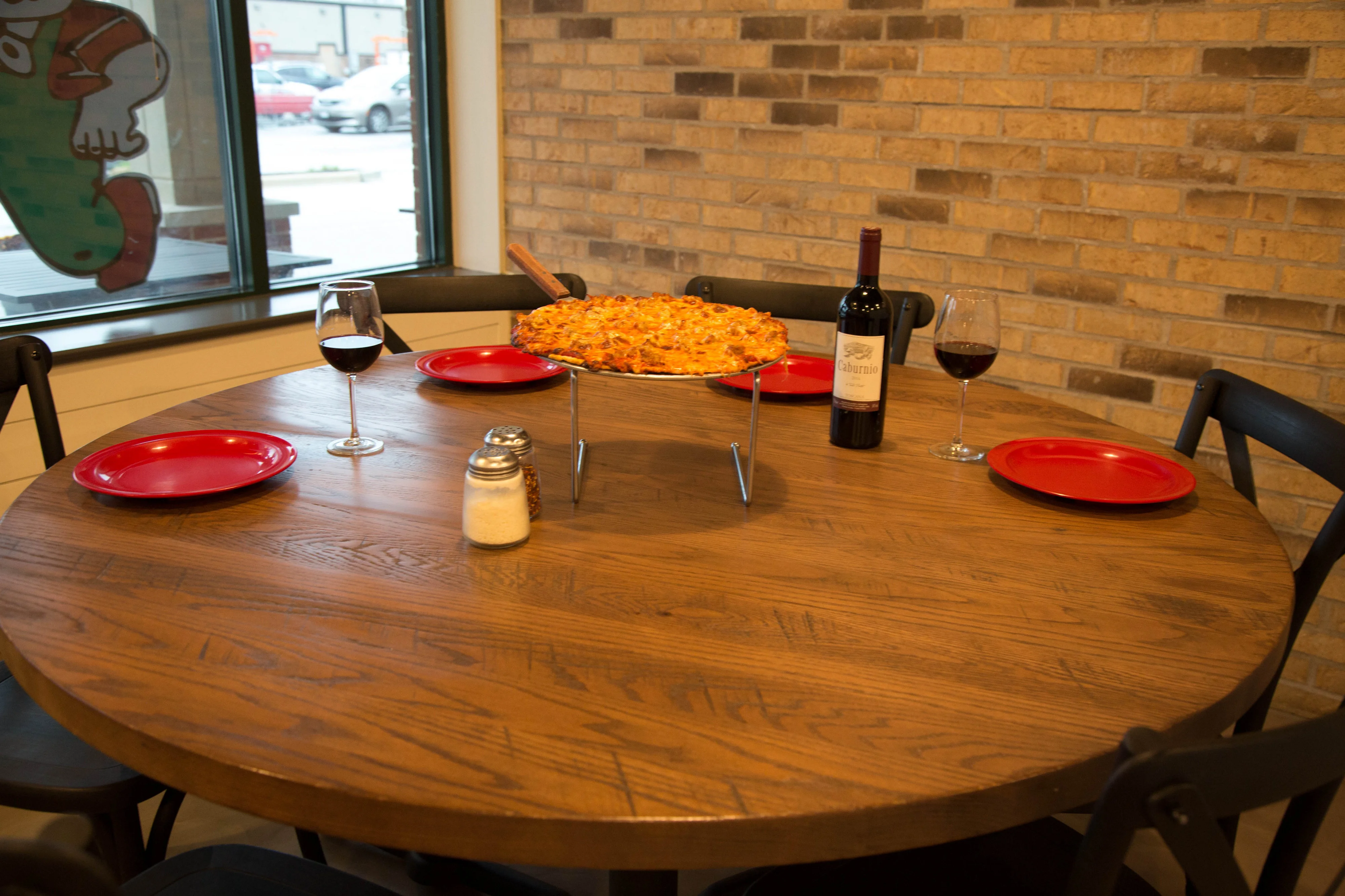 Delicious pepperoni pizza on a wooden table with red plates and wine
