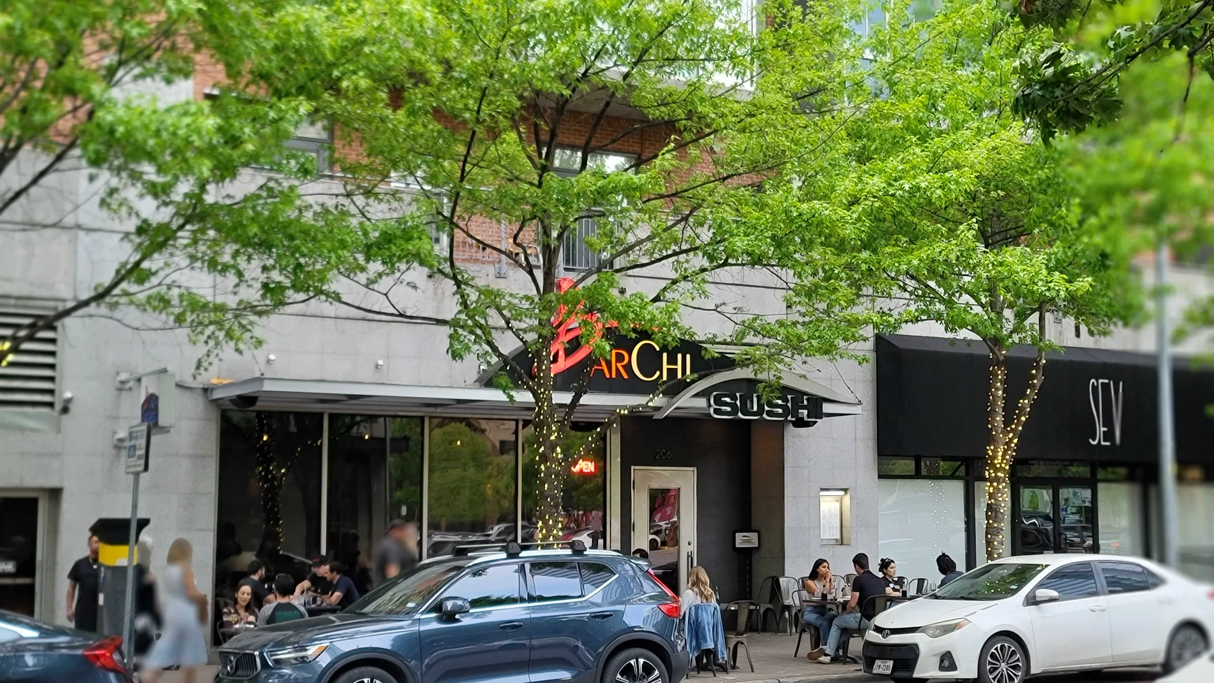 Sushi restaurant exterior with outdoor seating and greenery