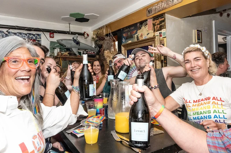 Group of friends celebrating with drinks at a lively restaurant.