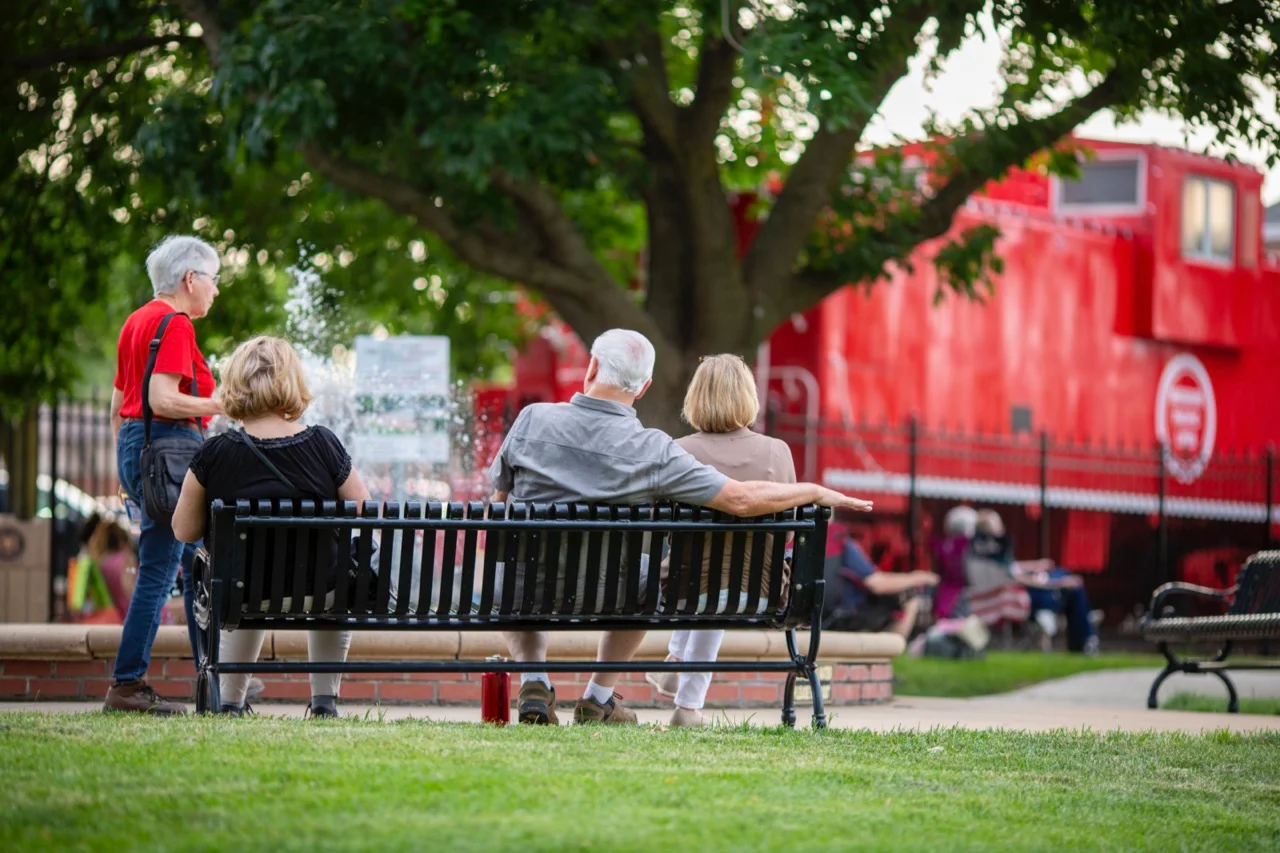 People sitting on a bench in front of the lee's summit, Missouri caboose train 