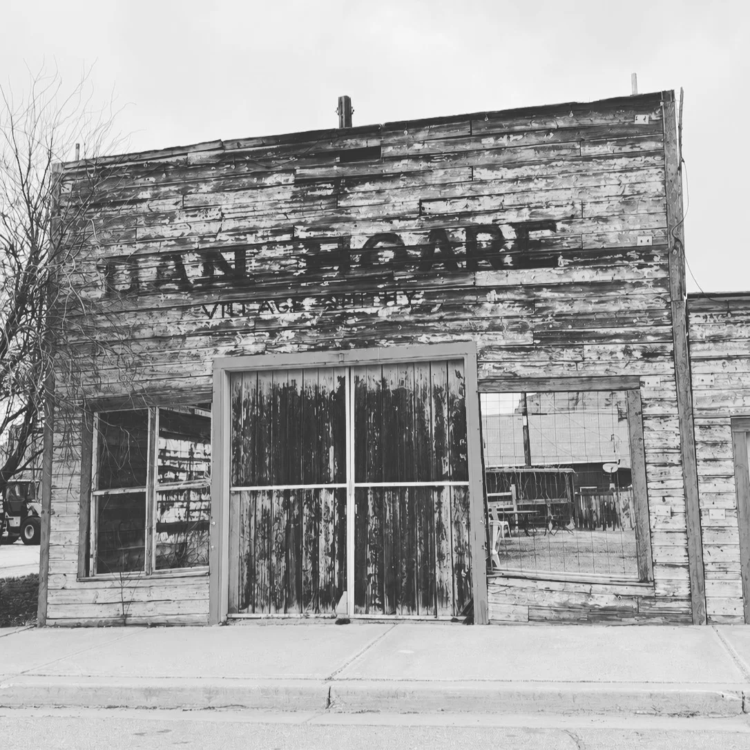 Weathered wooden building with large windows and a rustic appearance.