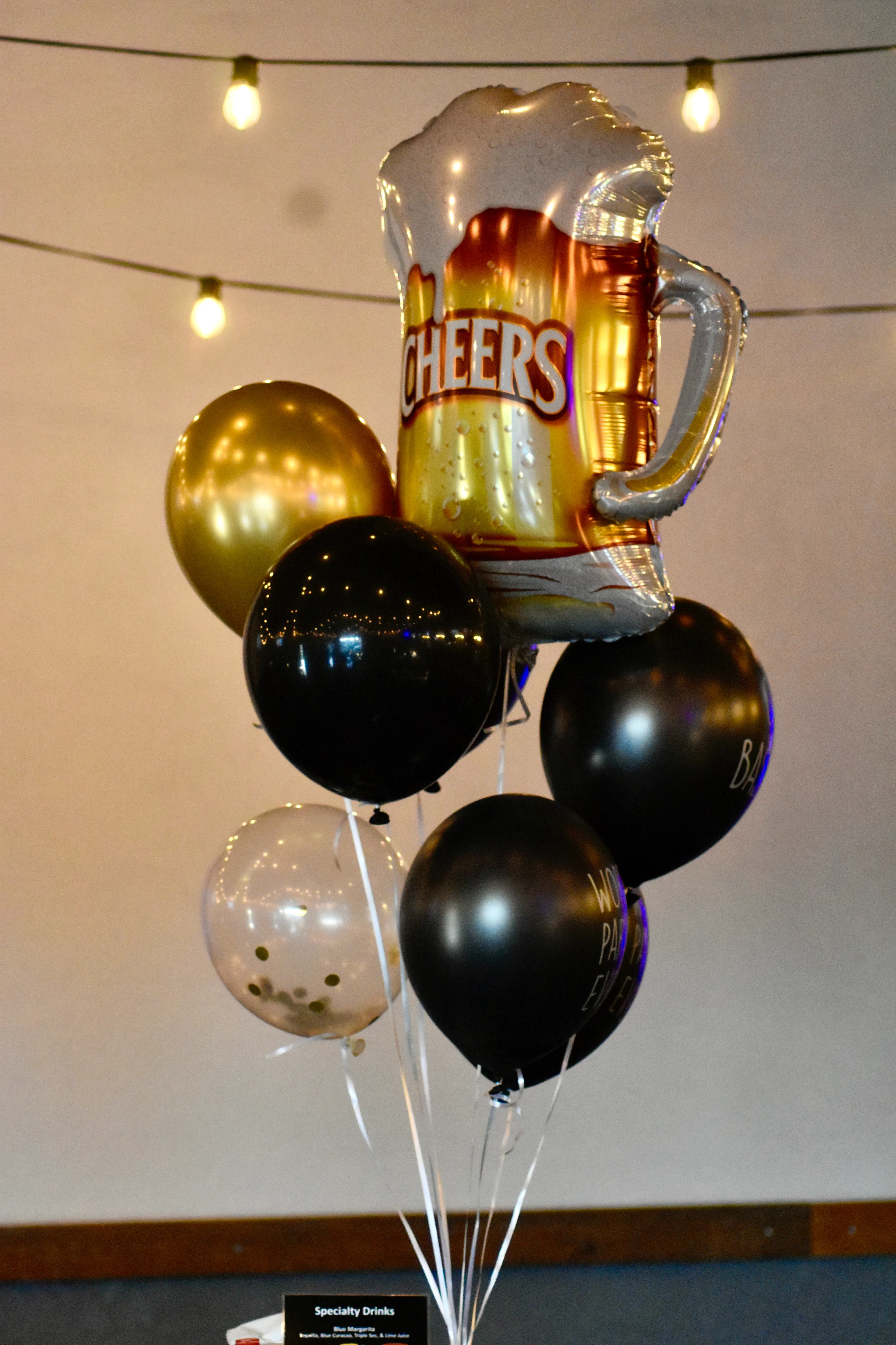 Festive balloon arrangement with beer mug and black, gold balloons