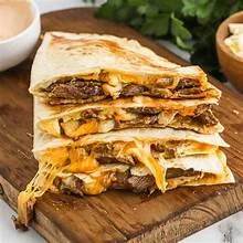 Cheesy beef quesadilla stacked on a wooden board
