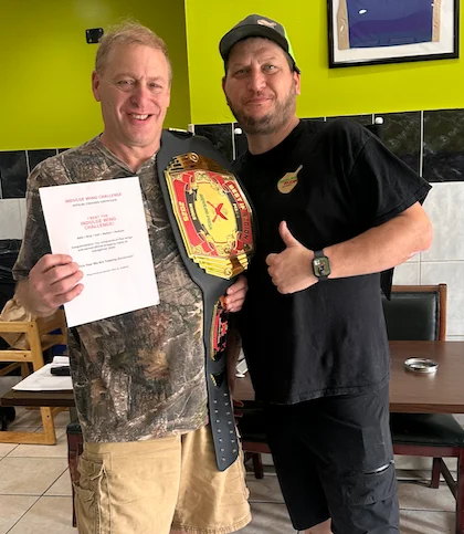 Two men celebrating a food challenge victory in a restaurant