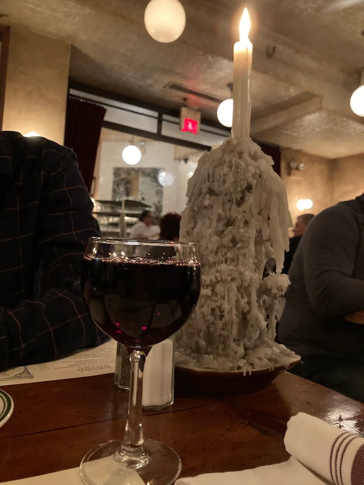 Elegant red wine glass beside a candle in a cozy restaurant setting