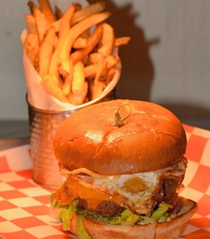 A delicious burger with lettuce, cheese, and a fried egg, served with fries.