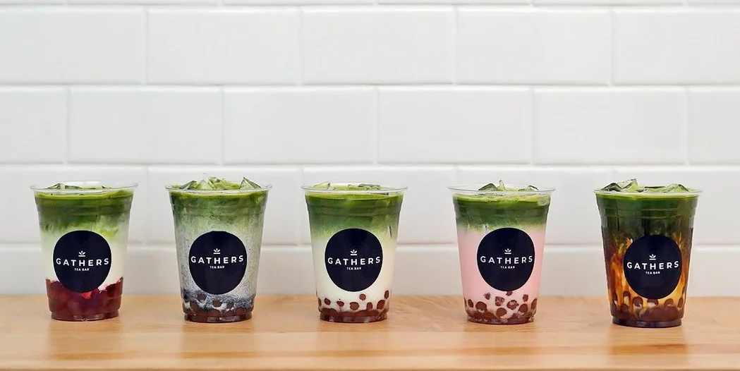 Colorful bubble tea drinks in clear cups on a wooden counter