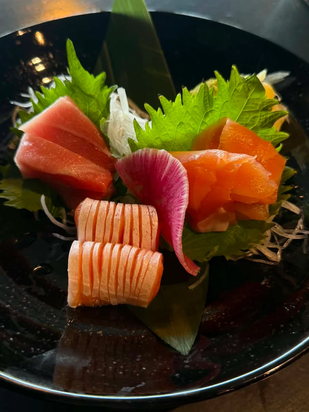 A plate of assorted sushi including salmon, tuna, and garnishes.