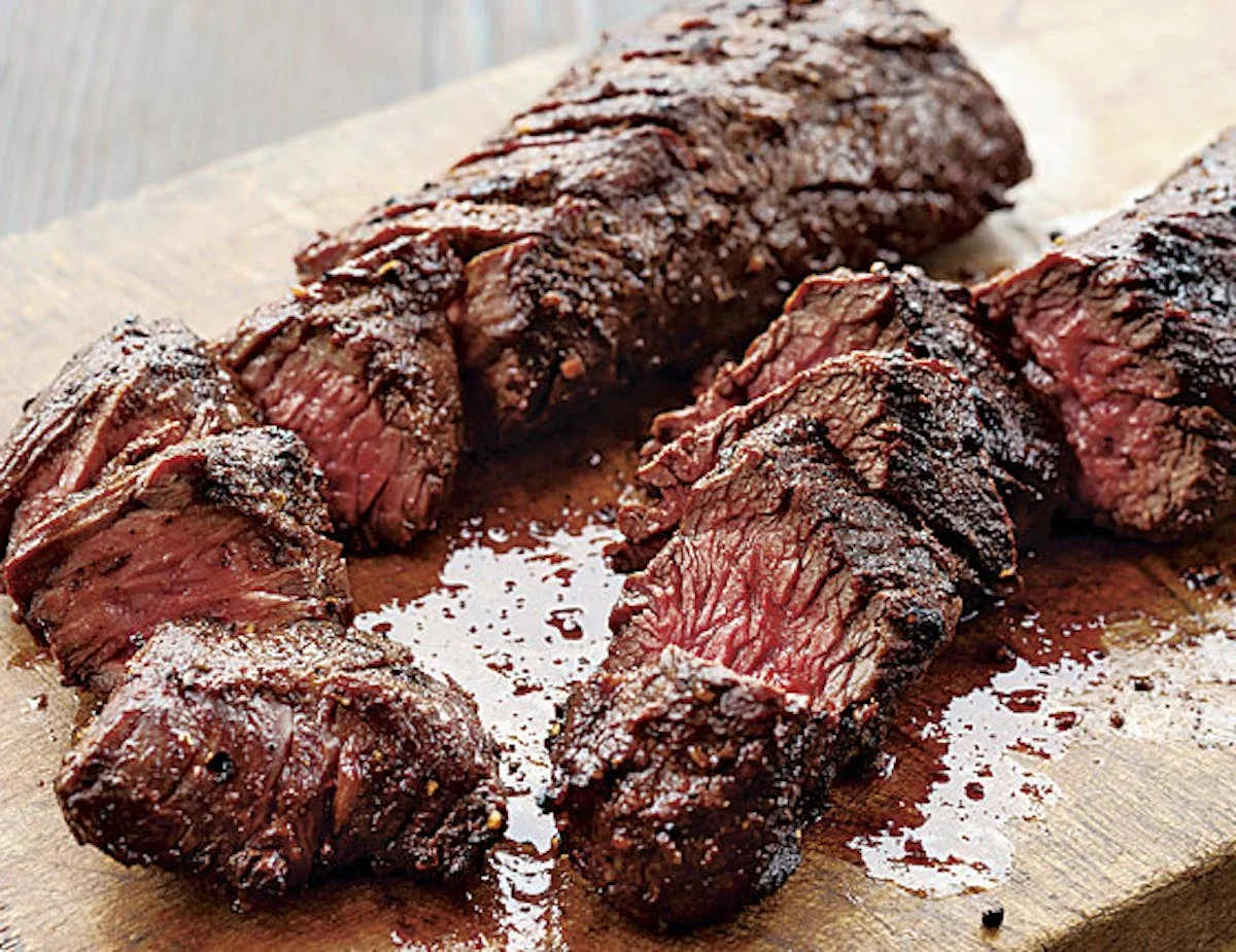 Sliced smoked brisket on a wooden cutting board, showcasing BBQ style