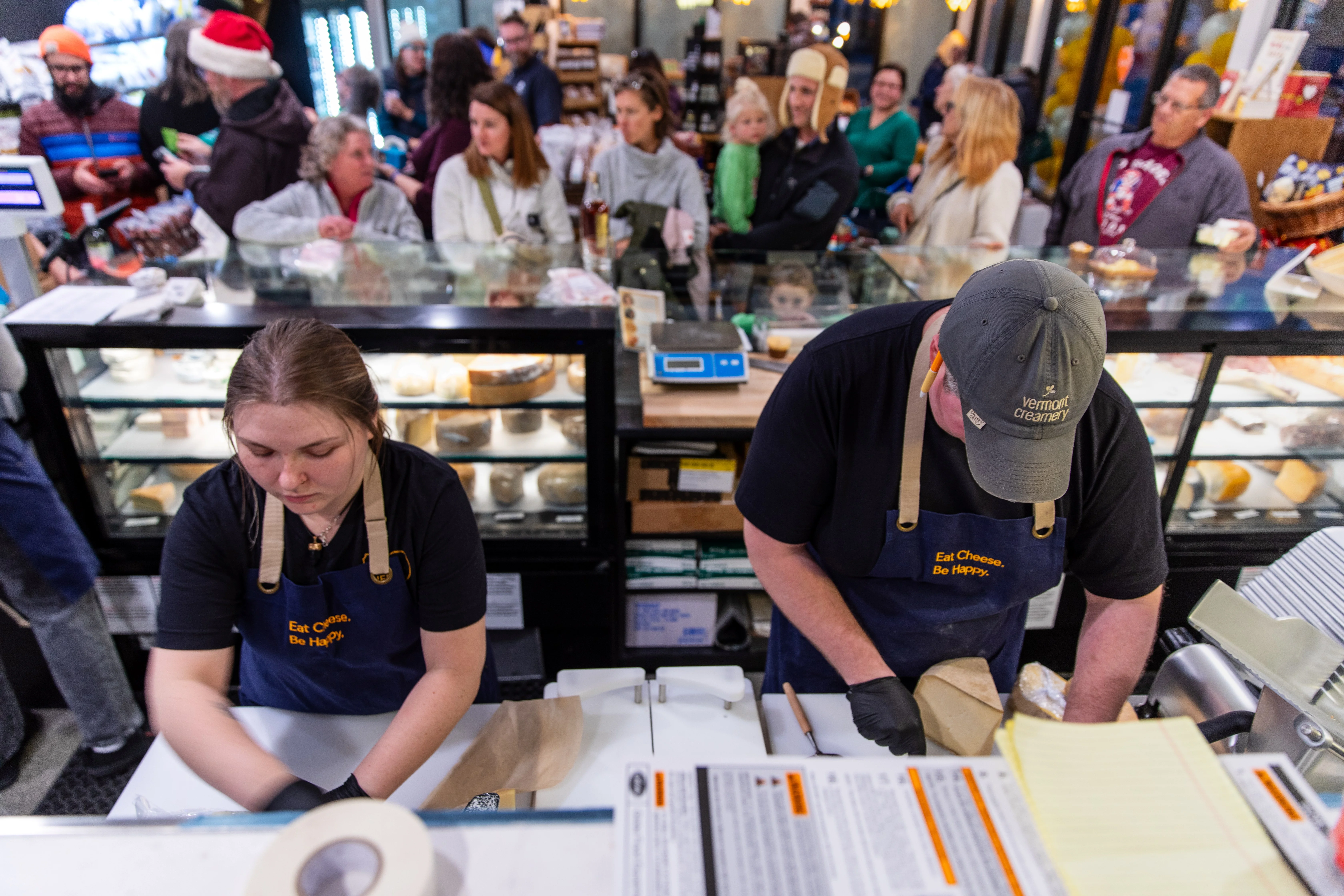 Busy cheese shop with staff preparing orders during holiday season