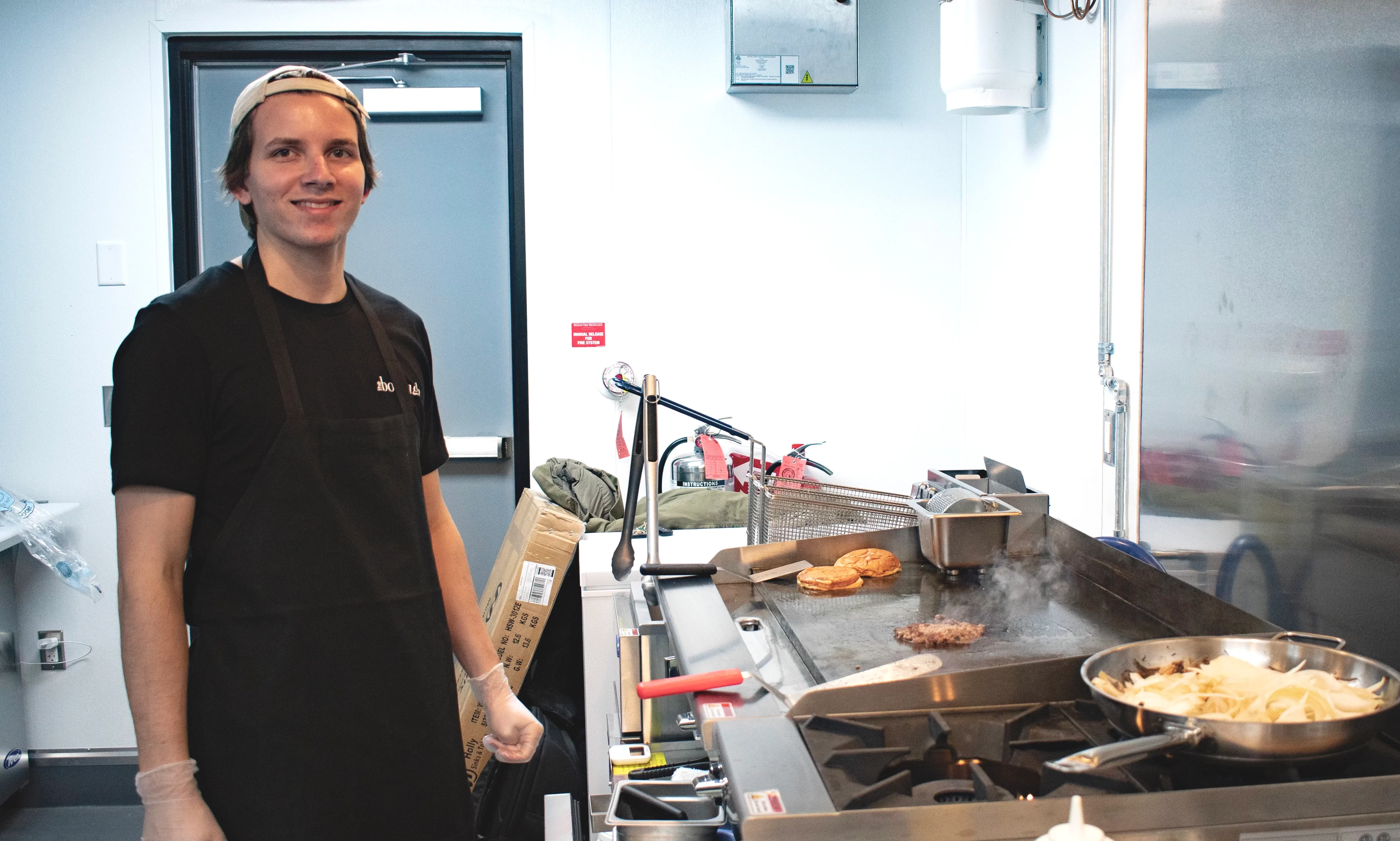 Borough Employee smiling while cooking a burger at the flattop.