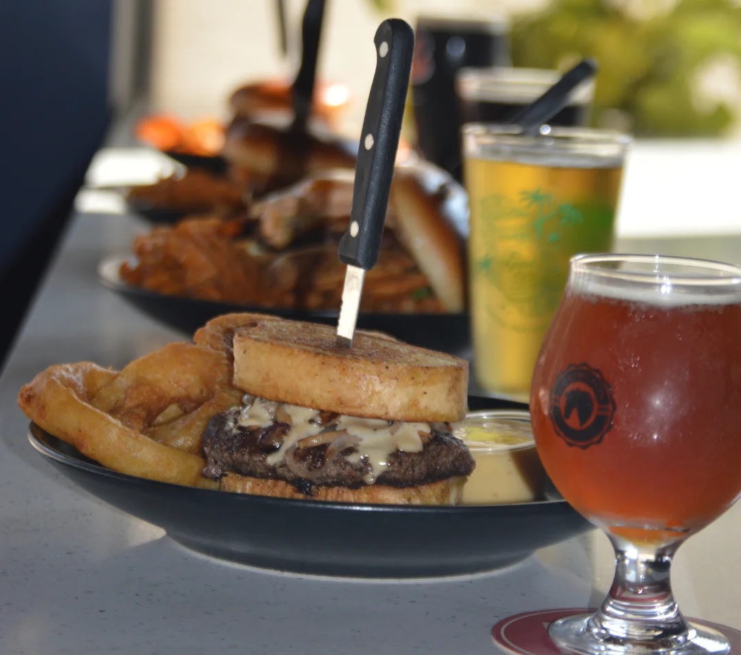 Juicy cheeseburger with a knife, served with onion rings and craft beer