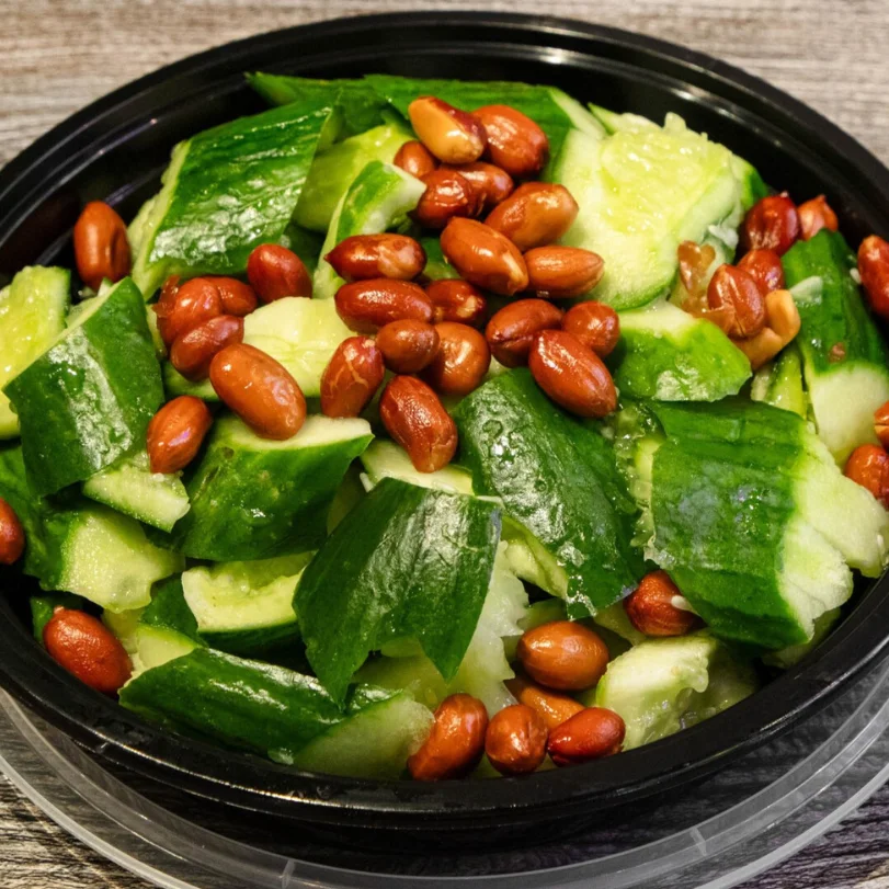 Fresh cucumber salad with peanuts in a black bowl.