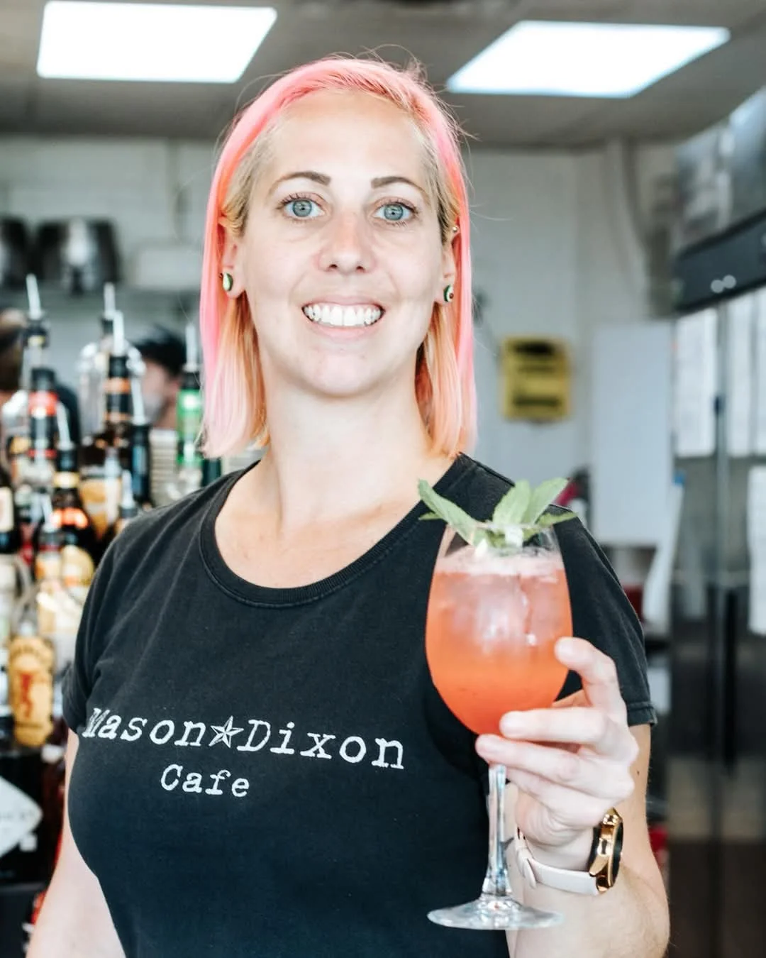 Bartender showcasing a vibrant cocktail at Mason-Dixon Cafe