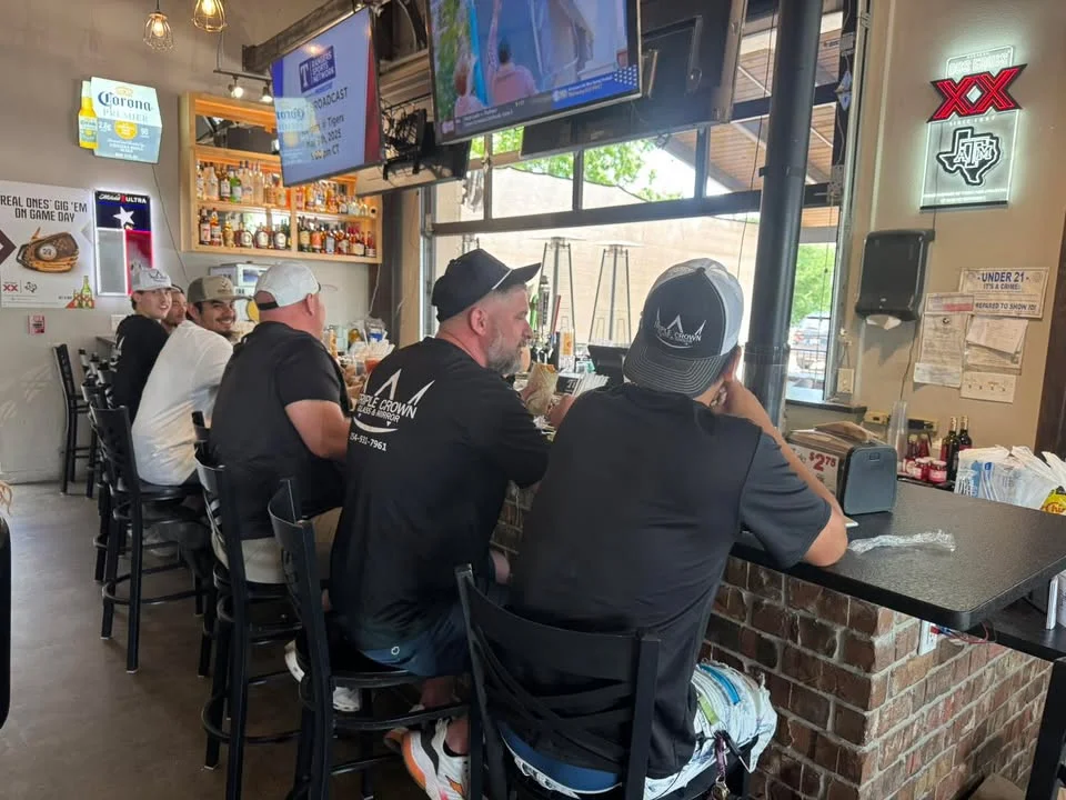 Casual bar scene with patrons enjoying drinks and sports on TV