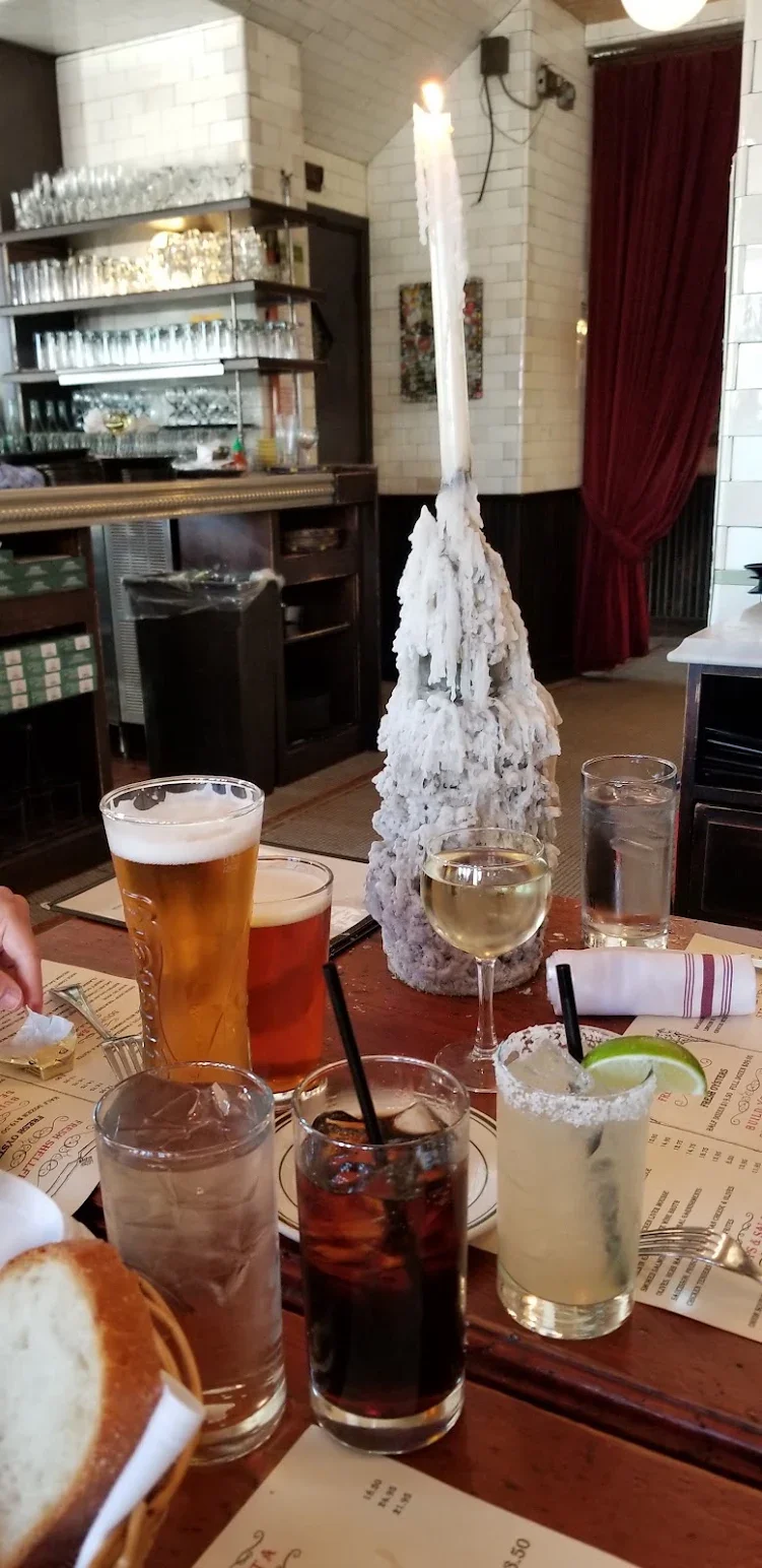 Variety of cocktails and drinks on a restaurant table with a candle centerpiece