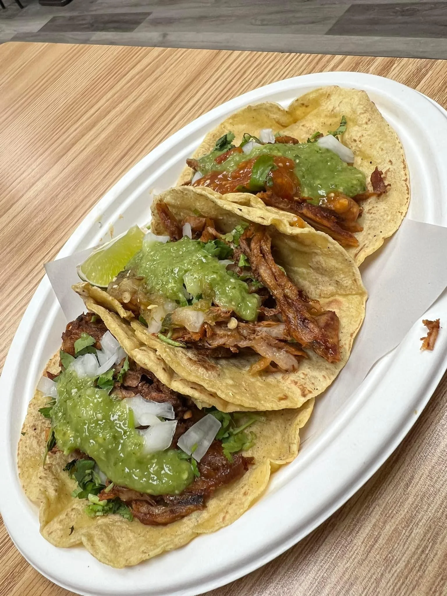 Three delicious tacos al pastor with green salsa