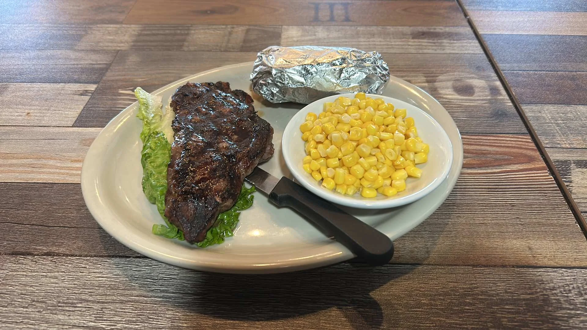 Grilled steak with corn and baked potato on a plate