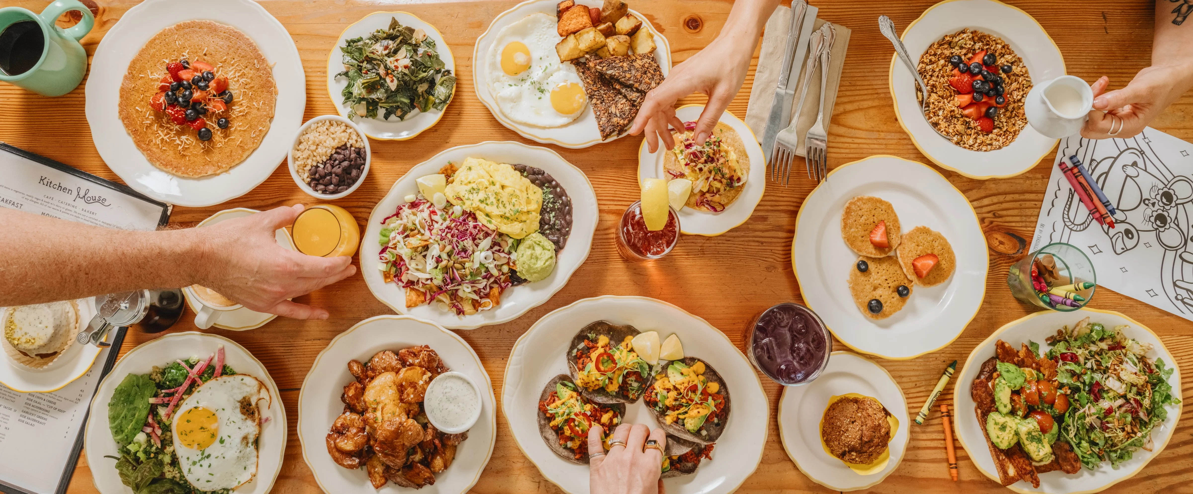 Breakfast spread with Chilaquiles, pancakes, jackfruit tacos, smashed potatoes, and morning glory bowl with orange juice, pastries, and iced tea