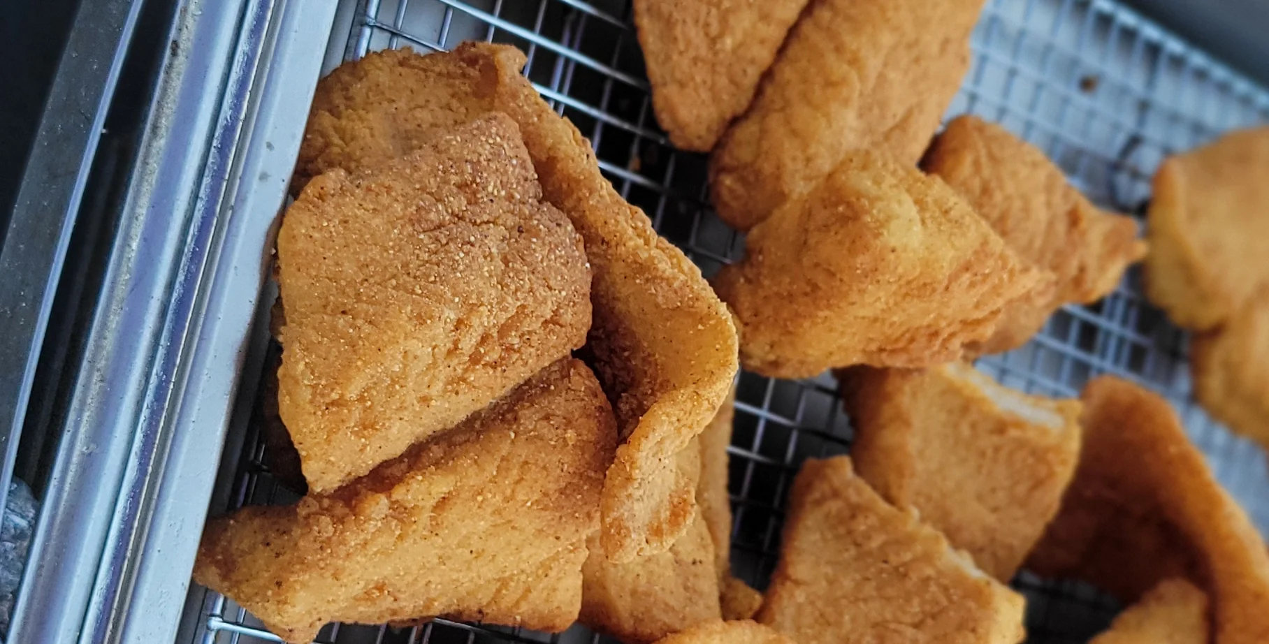 Crispy Southern fried catfish pieces on a cooling rack