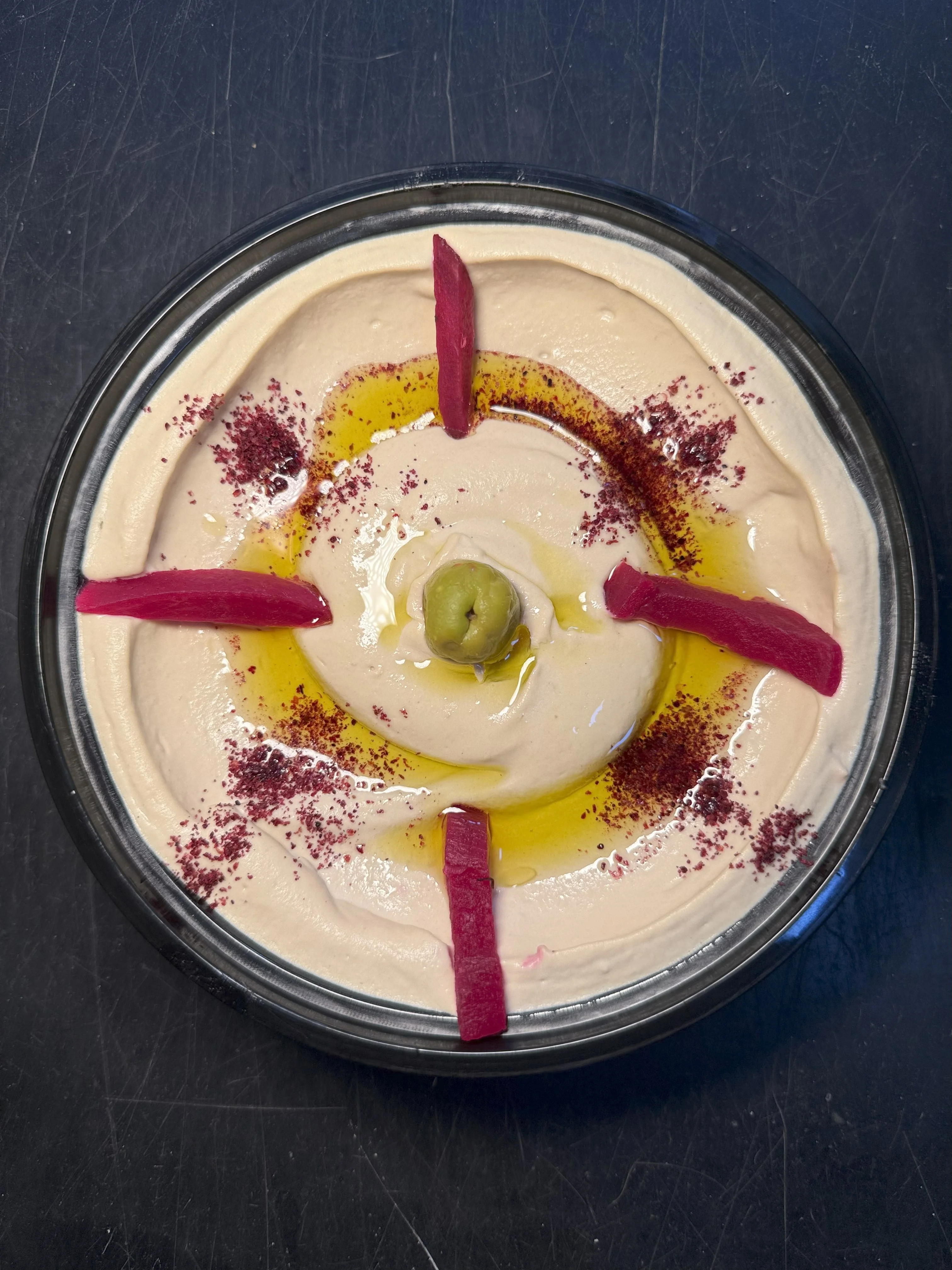 Creamy hummus topped with olive oil and pickled vegetables