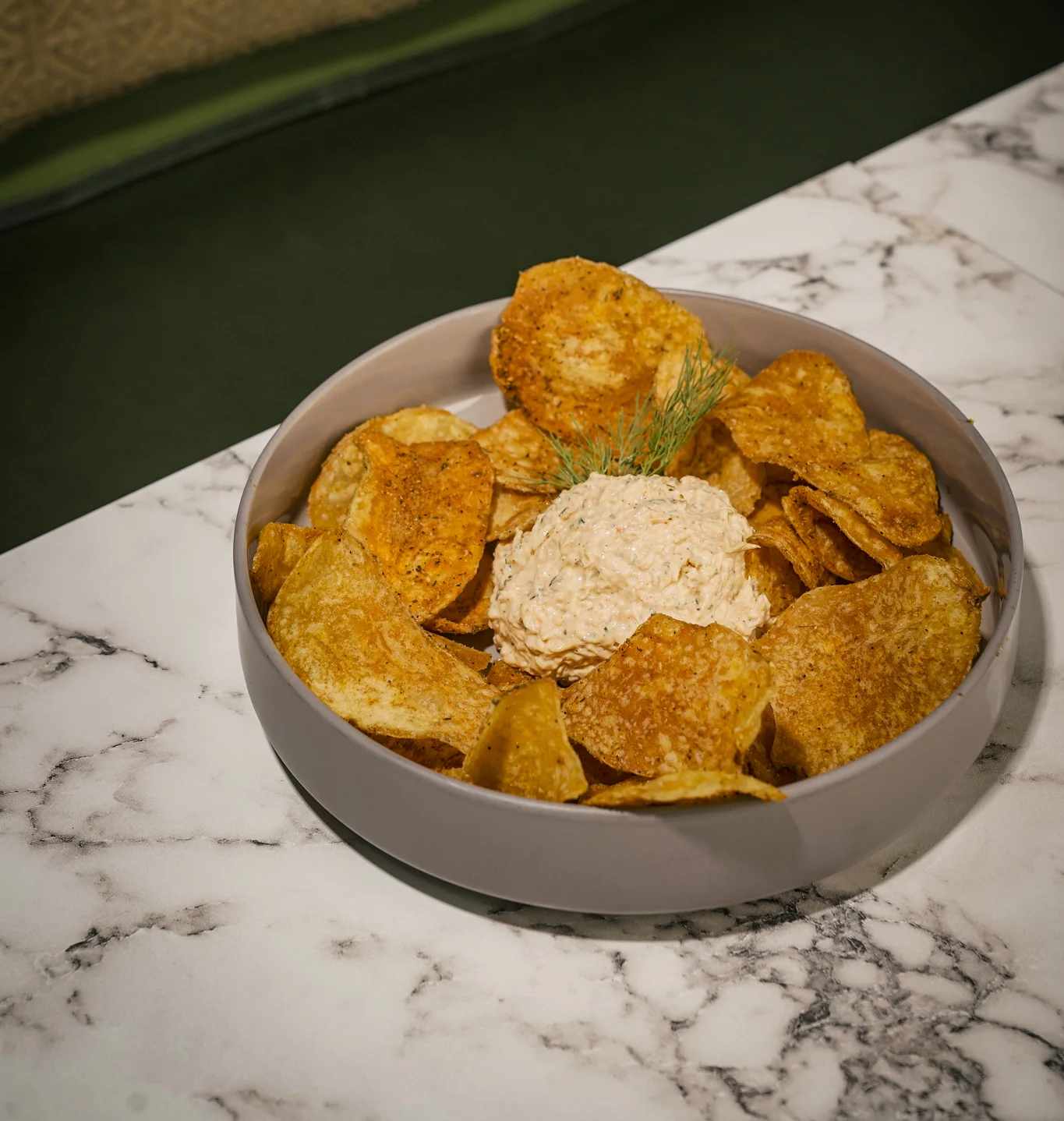 Crispy potato chips with creamy dip in a modern bowl