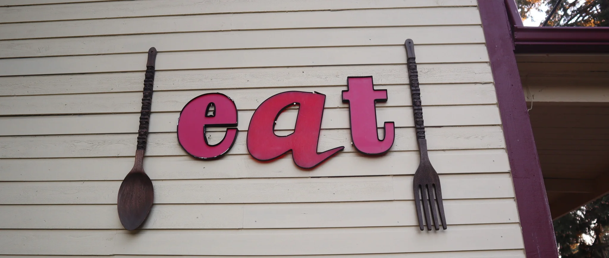 Restaurant sign with 'eat' in bold letters and wooden utensils