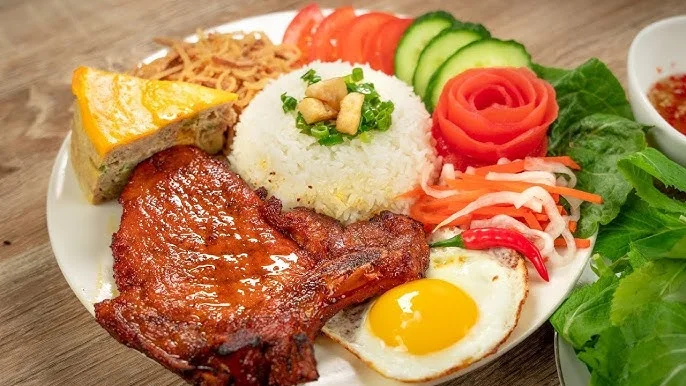 A vibrant plate of grilled chicken, rice, vegetables, and a fried egg.