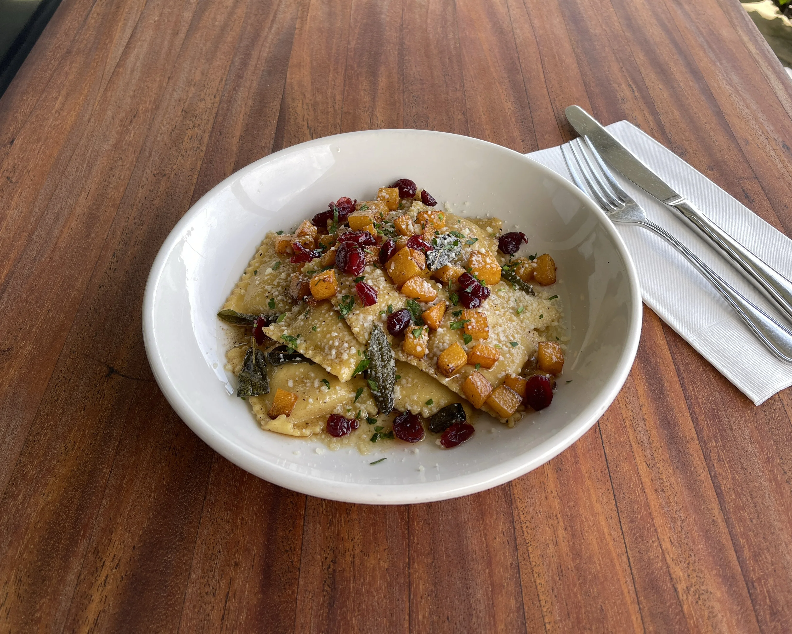 Italian pasta with roasted squash and cranberries on a white plate