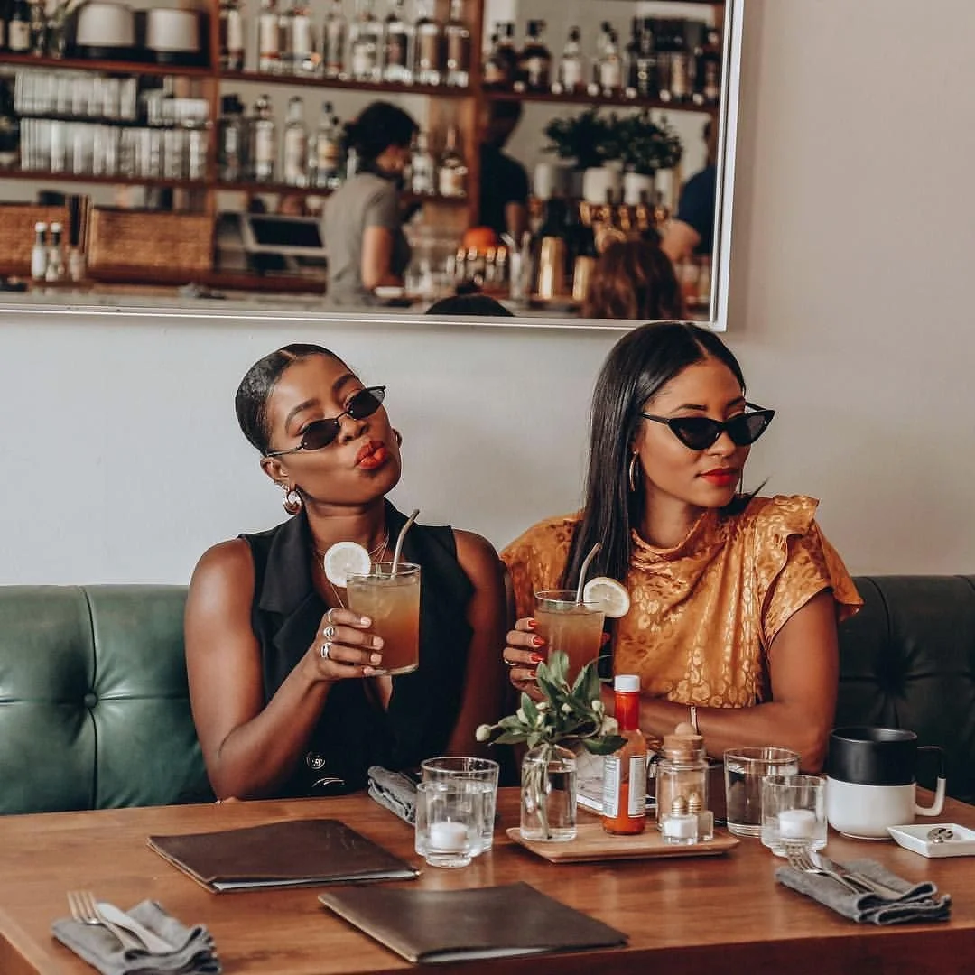 Two friends enjoying cocktails in a stylish restaurant setting
