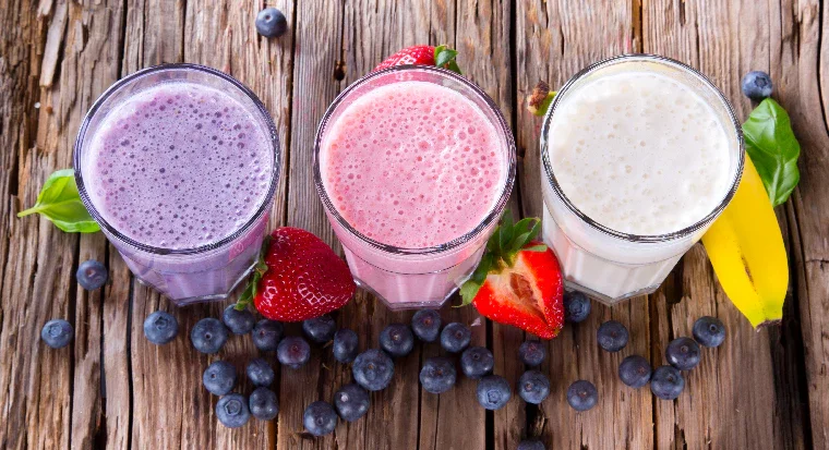 Colorful fruit smoothies in glasses on rustic wooden table